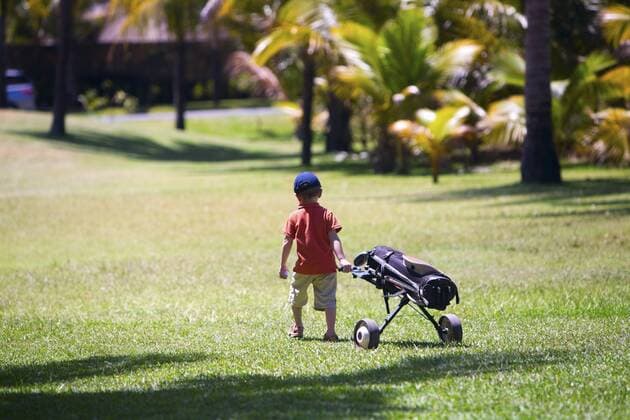 kleiner Junge laeuft mit Golftasche ueber den Golfplatz 4 years old boy walking with golf bag BLWS234328