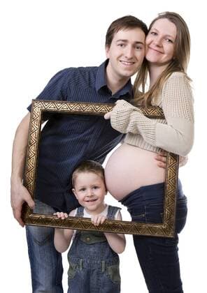 Familie mit kleinem Jungen erwartet ein neues Baby, laesst sich mit Bilderrahmen fotografieren family with small boy expecting another baby BLWS234335
