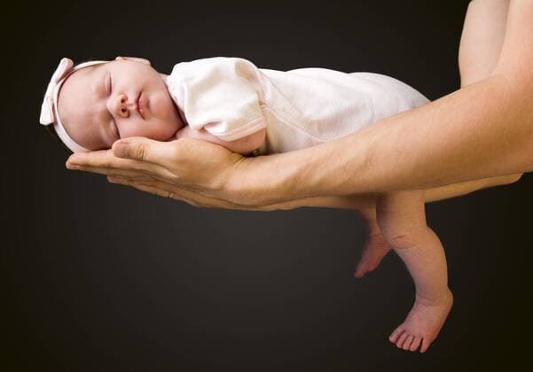 Schuetzende Haende. Vater haelt ein 14 Tage altes Baby in seinen Armen Supporting Hands. Father holding his 14 days old baby girl on his arms BLWS238338
