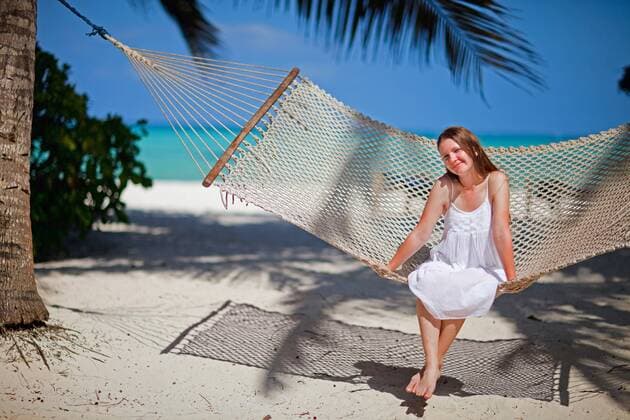 eine junge huebsche Frau sitzt in einer Haengematte am tropischen Strand a young attractive woman sitting in a hammock at tropical beach BLWS269797