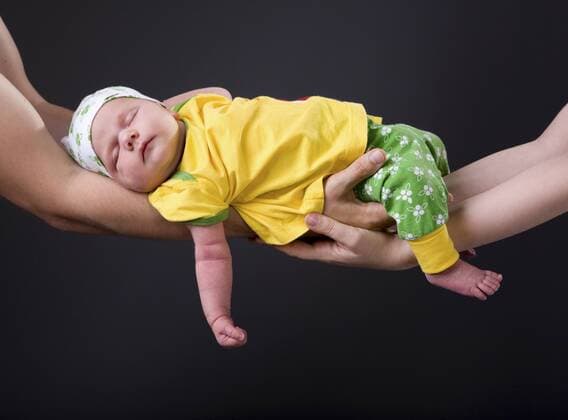schlafendes Baby wird von den Eltern auf den Haenden gehalten Supporting Hands. Parents holding 14 days old baby girl on theirs arms BLWS233182