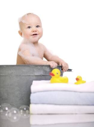 kleines Baby sitzt in einer Waschschuessel und nimmt ein Schaumbad Bath Time. Cute happy baby girl having bath BLWS233205