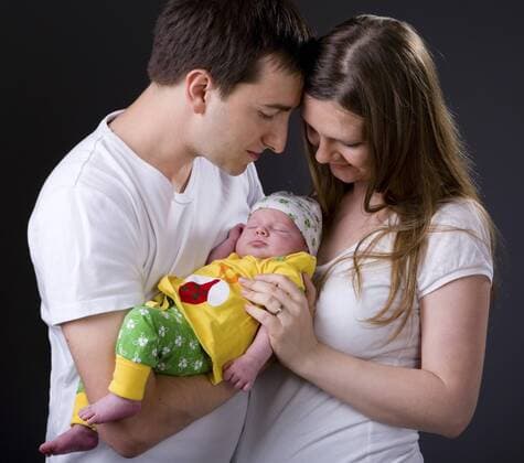 junges Paar mit ihrem neugeborenen Kind auf dem Arm Happy young parents and newborn girl BLWS234321