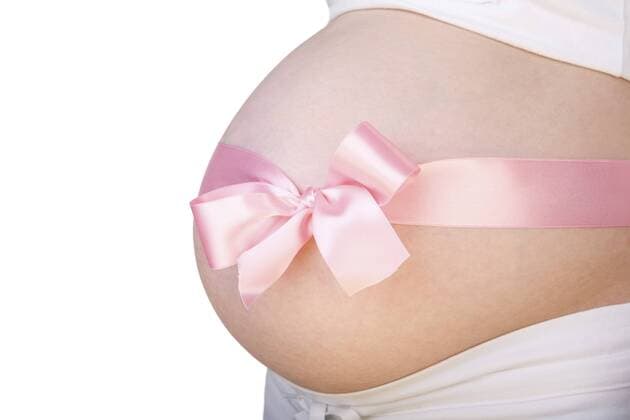 Bauch einer Schwangeren, mit einer Schleife verziert pregnant belly with pink bow over it BLWS234333