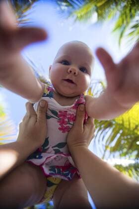 4 Monate altes Baby wird im Urlaub in die Luft gehalten 4 months baby girl on vacation in tropical country BLWS237820