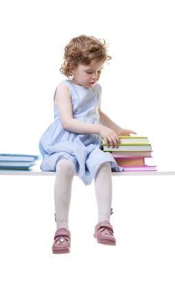 kleines Maedchen sitzt mit einem Stapel Schulbuechern auf einer Bank Little girl with books sitting on an bench BLWS237851