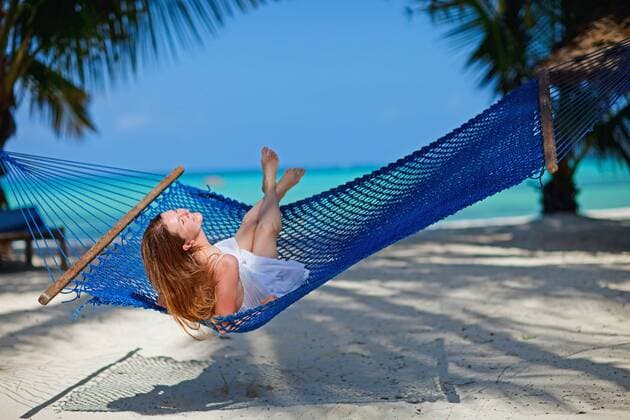 eine junge huebsche Frau liegt in einer Haengematte am tropischen Strand a young attractive woman lying in a hammock at tropical beach BLWS269796