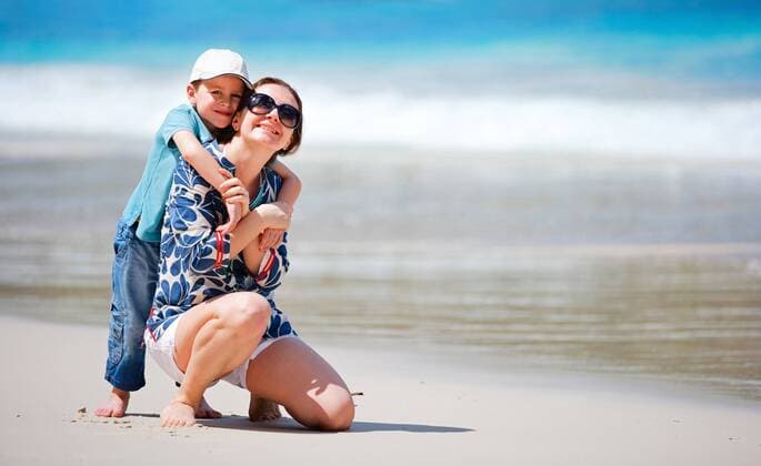 ein kleiner Junge umarmt seine Mutter an einem Sandstrand a little boy embracing his mother on sandy beach BLWS269837