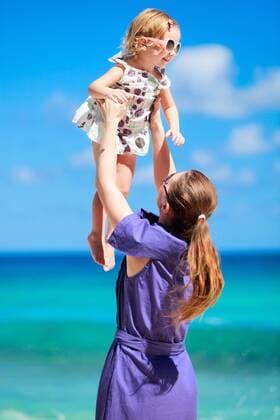 eine junge Mutter hebt ihre kleine Tochter am tropischen Strand hoch a young mother lifting up her little daughter on tropical beach BLWS270806