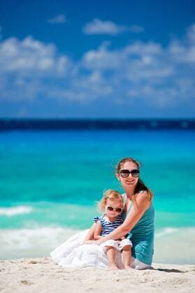 junge Mutter sitzt mit ihrer kleinen Tochter am Sandstrand young mother and her daughter sitting on sandy beach BLWS270935