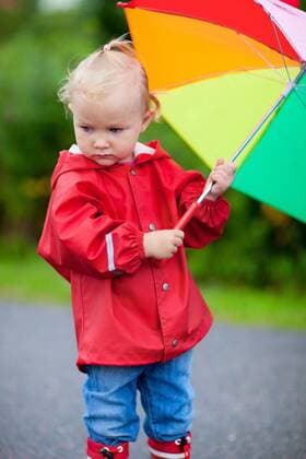 kleines Maedchen in Regenkleidung mit geoeffnetem Regenschirm little girl in rain clothes with opened umbrella BLWS272231