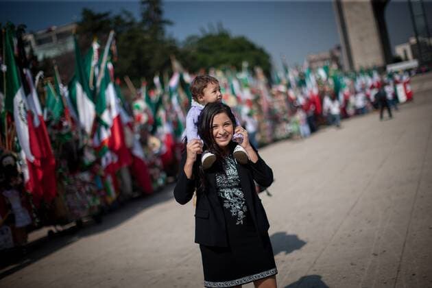 (150901) -- MEXICO CITY, Sept. 1, 2015 -- A woman carries her child in front of the sellers of ornaments and Mexican national flags, ahead of the celebration of the 205th Anniversary of Mexico s Independence, in the forecourt of the Monument to the Revolution, in Mexico City, capital of Mexico, on Sept. 1, 2015. ) (rtg) MEXICO-MEXICO CITY-SOCIETY-INDEPENDENCE DAY PedroxMera 