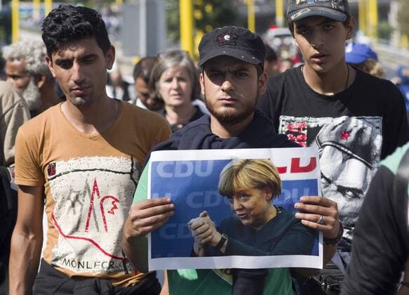 refugees and migrants on foot to the West, Budapest, Hungary UNGARN, 04.09.2015, Budapest - XI. Bezirk.Fuer die grosse Zahl auf der Balkanroute ankommender Fluechtlinge und Migranten ist der Ostbahnhof (Keleti p‡lyaudvar) zum Fluehtlingslager geworden. Nach Tagen der Zugverkehrssperre entscheiden sie sich, zu Fuss knapp 200 km nach Oesterreich zu marschieren. -Unterwegs durch die Stadt Richtung Autobahn M1. Che-Guevara-Fans mit Bild der konservativen deutschen Kanzlerin Merkel. Fast alle wollen nach Deutschland. The Eastern railway station has become a sort of refugee camp for the numerous refugees and migrants arriving on the Balkan route. After days of train traffic blockade they decide to march to Austria on foot, around 200 km. -People walking the town towards the M1 motorway. Che Guevara fans with a picture of the conservative German chancellor Angela Merkel. Almost everybody want Copyright: MartinxFejer EST&OST Fejer150904083