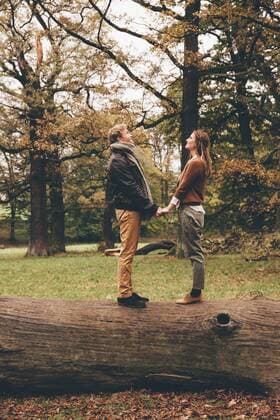 Young couple in love holding hands on a tree trunk in an autumnal park model released Symbolfoto  CHAF000202