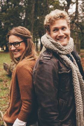 Happy young couple standing back to back in an autumnal park model released Symbolfoto  CHAF000205