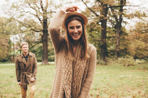 Portrait of young woman with hat in autumnal park with boyfriend in the background model released Symbolfoto  CHAF000210