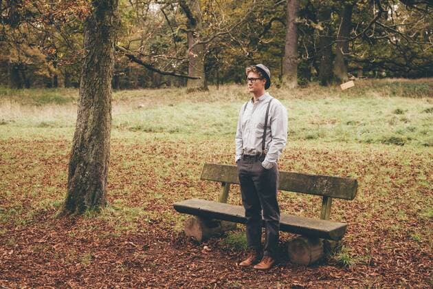 Young man standing in front of a bench in autumnal park looking at distance model released Symbolfoto  CHAF000222