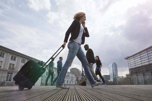 Woman on the phone walking with a rolling suitcase in the city model released Symbolfoto  STKF001437