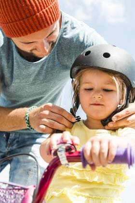 Father closing daughter s helmet on bike model released Symbolfoto  UUF005186