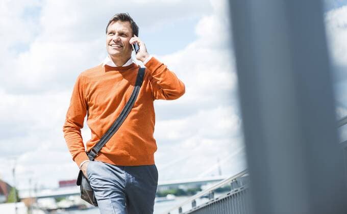 Businessman with shoulder bag walking while talking on the phone model released Symbolfoto  UUF005243
