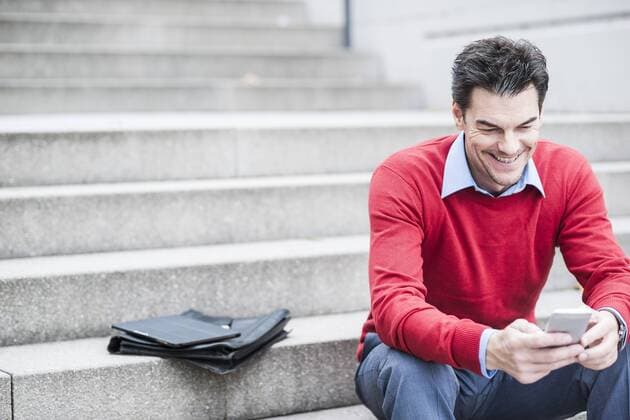 Businessman sitting on stairs looking at his smartphone model released Symbolfoto  UUF005378