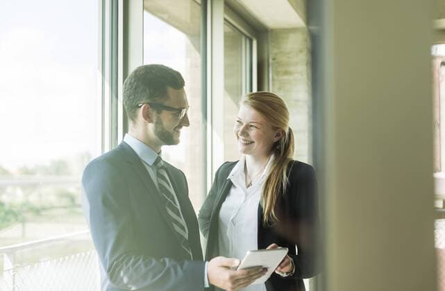 Smiling young businessman and businesswoman at the windowwith digital tablet model released Symbolfoto property released  UUF005418