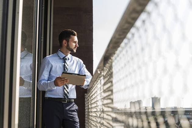 Young businessman standing on balcony with digital tablet model released Symbolfoto property released  UUF005471