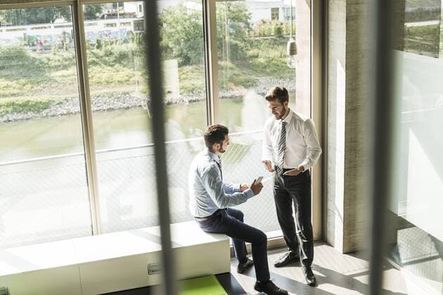 Two young businessmen with smartphones discussing model released Symbolfoto property released  UUF005475