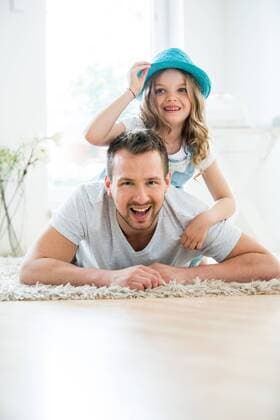 Father and daughter lying on floor, girl playing with hat model released Symbolfoto property released  WESTF021520