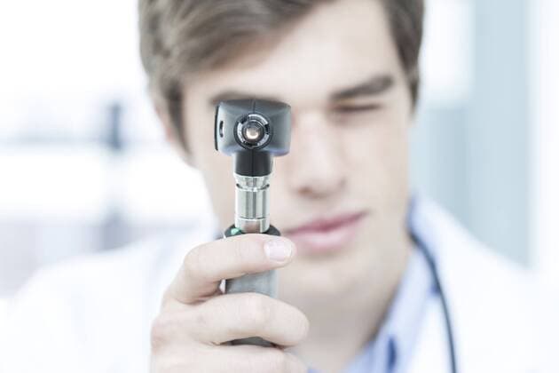 Doctor looking through otoscope model released Symbolfoto property released  ZEF006497