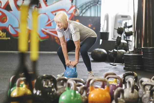 Senior woman in gym lifting kettlebell model released Symbolfoto property released  MADF000510