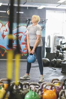 Senior woman in gym lifting kettlebell model released Symbolfoto property released  MADF000511