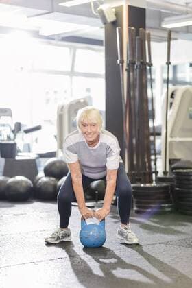 Senior woman in gym lifting kettlebell model released Symbolfoto property released  MADF000512