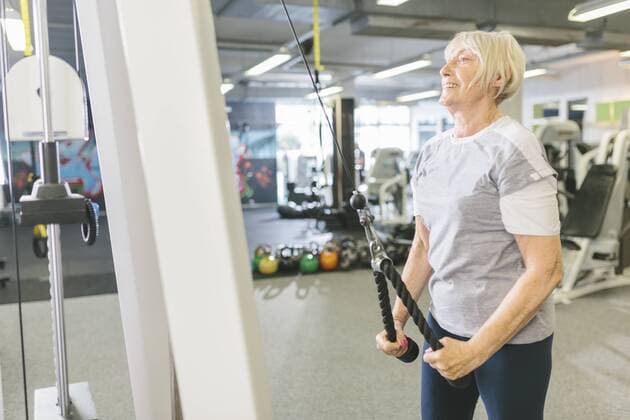 Smiling senior woman in gym exercising at cable machine model released Symbolfoto property released  MADF000520