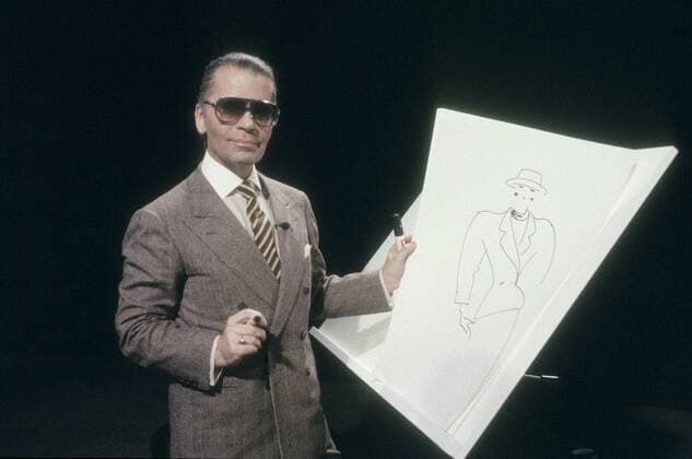 Karl Lagerfeld (Modeschöpfer) 09 84 piel Karl Lagerfeld im September 1984 Deutschland Deutscher deutsch Mann Design Designer Mode Kostümbildner Fotograf Modedesign Modemacher Modedesigner german fashion designer photographer dunkelhaarig Zopf seriös Anzug quer halb stehend Modezeichnung