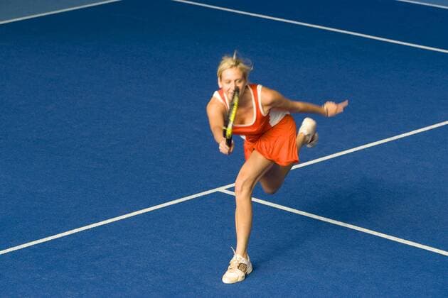 IMAGO Creative, Neujahr, Vorsätze, Sport Frau in roter Sportbekleidung beim Tennisspielen in der Halle woman in red sportswear playing indoor tennis BLWS129197