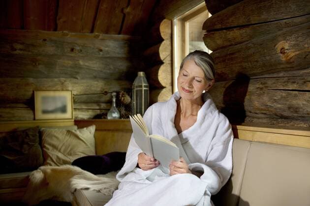 Smiling senior woman sitting on bench in bathrobe reading a book model released Symbolfoto property released  TOYF001291