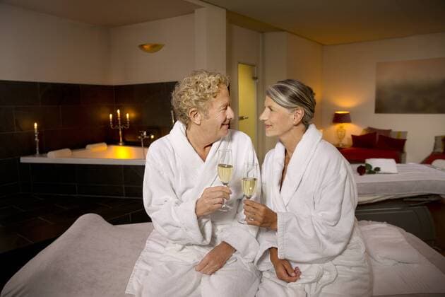 Smiling senior couple in bathrobes clinking champagne glasses model released Symbolfoto property released  TOYF001322