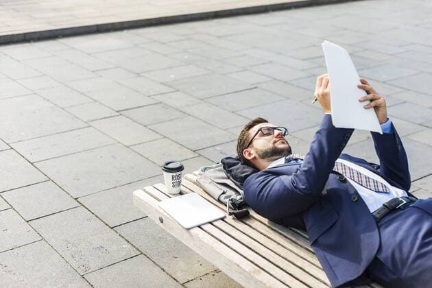 Young businessman lying on bench, working model released Symbolfoto  UUF005588