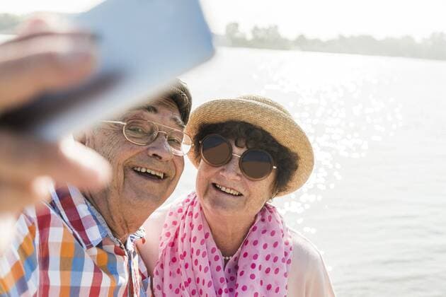 Senior couple taking a selfie at riverside model released Symbolfoto  UUF005672
