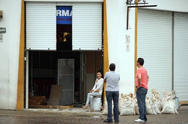 People are seen in front of a closed business, moments before the arrival of hurricane Patricia, in Puerto Vallarta, Jalisco state, Mexico, on Oct. 23, 2015. Hurricane Patricia made landfall on the Pacific coast of Mexico at around 5:40 p.m., local time, Friday, hitting the municipality of La Huerta in the state of Jalisco. ) (da) MEXICO-PUERTO VALLARTA-ENVIRONMENT-HURRICANE DAVIDxDIAZ 