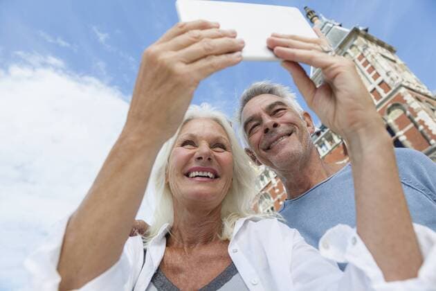 Netherlands, Amsterdam, senior couple taking a selfie in front of central station model released Symbolfoto  FMKF002051