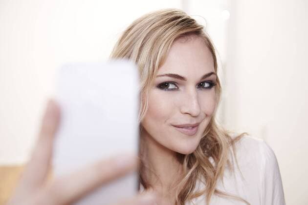 Smiling young woman taking selfie model released Symbolfoto property released  FMKF002198