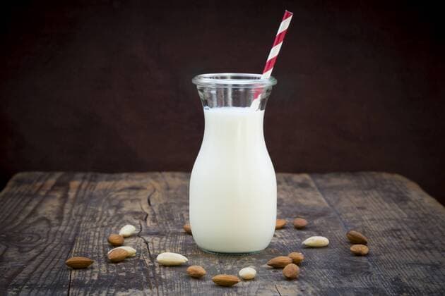 Almond milk in glass, drinking straw, on wood  LVF003876
