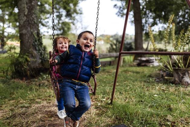 Two little children playing with swing in a garden  MGOF000809