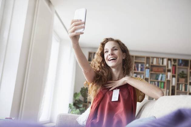 Happy woman at home taking a selfie with new garment model released Symbolfoto property released  RBF003131