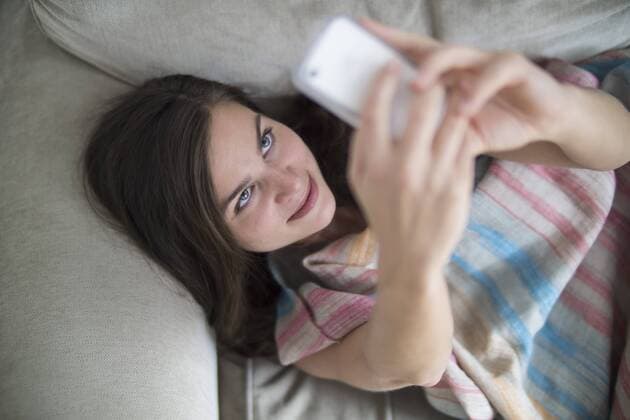 Young woman relaxing on couch, taking selfie with smart phone model released Symbolfoto property released  RIBF000172