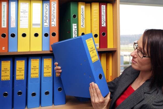 Bueroangestellte nimmt Aktenordner aus Regal woman clerk takes files from filing cabinet BLWS162149