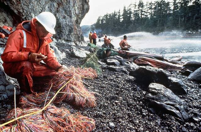 March 28, 1989 - Prince William Sound, AK, United States of America - A Coast Guardsman checks oil recovery mesh as others steam blast rocks and shorelines soak by with crude oil spilled from the Exxon Valdez after running aground on Bligh Reef in Prince William Sound spilling at least 11 million gallons of crude oil in the pristine waters March 28, 1989 in Prince William Sound, Alaska. Prince William Sound United States of America - ZUMAp138