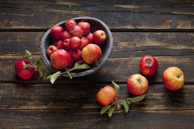 Bowl of different sorts of red apples on dark wood  CSF026578